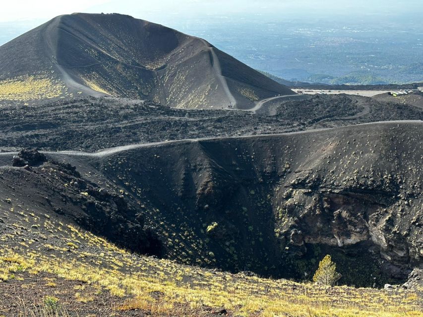 Catania: Etna Morning or Sunset Trek with Lava Tunnel & Gear - Entering a lava tube with a helmet and flashlight